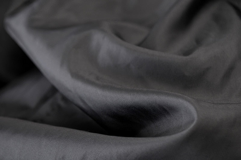 Close-up of soft black fabric with smooth texture, ideal for stylish vintage jackets and apparel.
