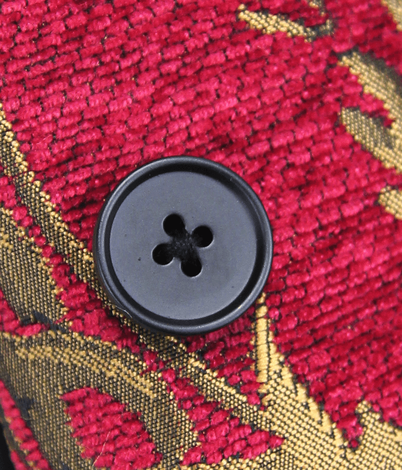 Close-up of a black button on a vintage red waistcoat with golden filigree details.