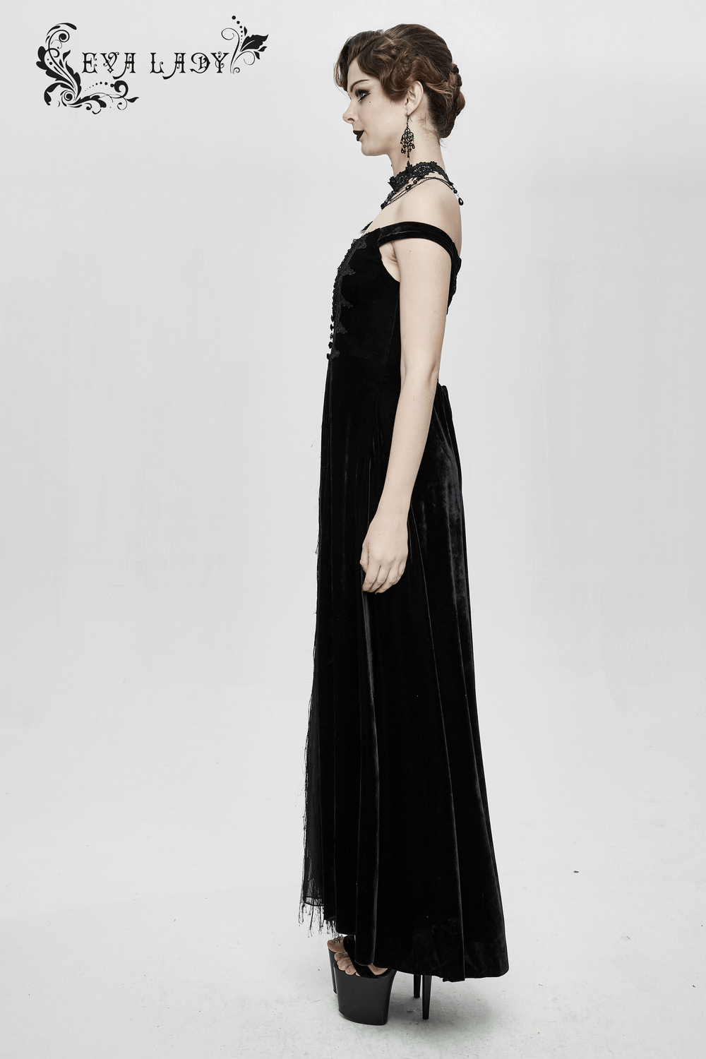 Elegant model in a vintage sexy black off shoulder velvet long dress with lace details and lace-up back.