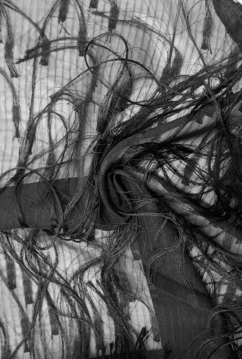 Close-up of elegant black fabric with intricate fringes, perfect for gothic styling and fashion design.