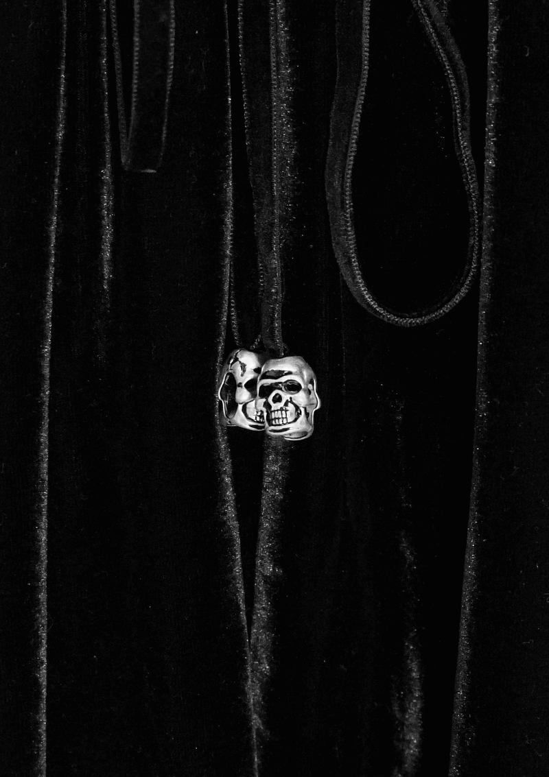 Gothic black velvet fabric with a silver skull accent hanging from a drawstring, adding a unique touch to a stylish dress.