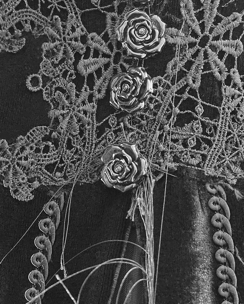 Close-up of lace detailing and decorative rose buttons on a vintage gothic black dress.