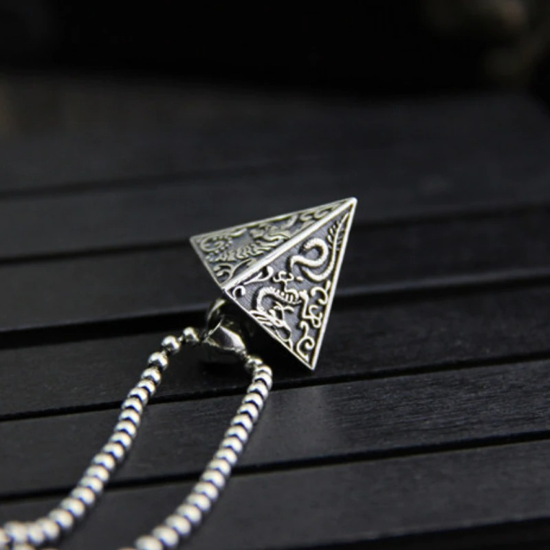 Vintage Thai silver pyramid pendant with intricate animal designs on a chain, perfect for stylish jewelry lovers.