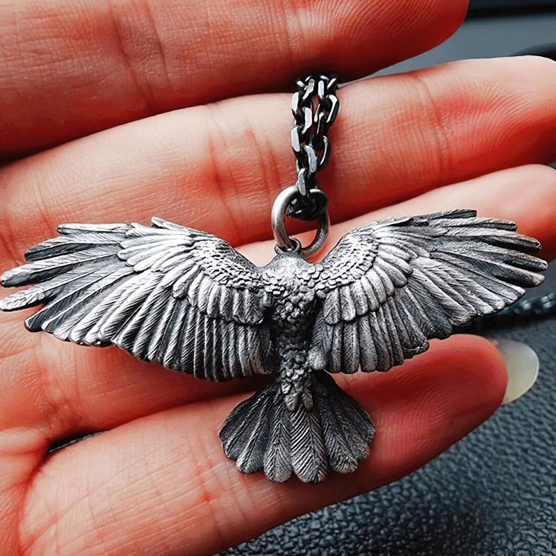 Vintage silver plated crow pendant necklace held in hand, showcasing intricate wing details and punk style.