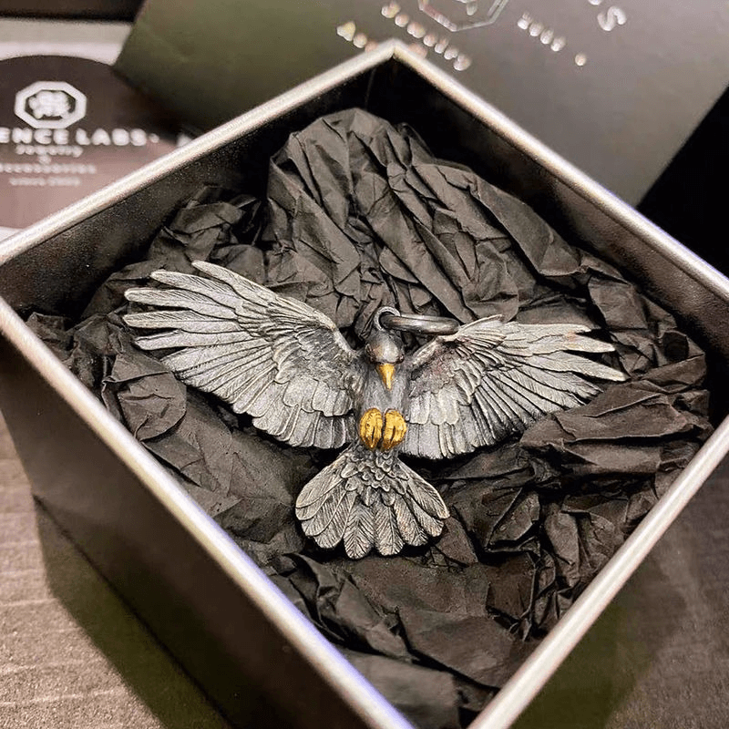 Vintage silver plated crow pendant in a gift box with crumpled black paper.