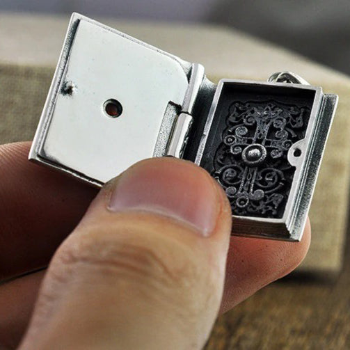 Vintage silver religious pendant in the shape of a book, showcasing intricate detailing and stylish design.