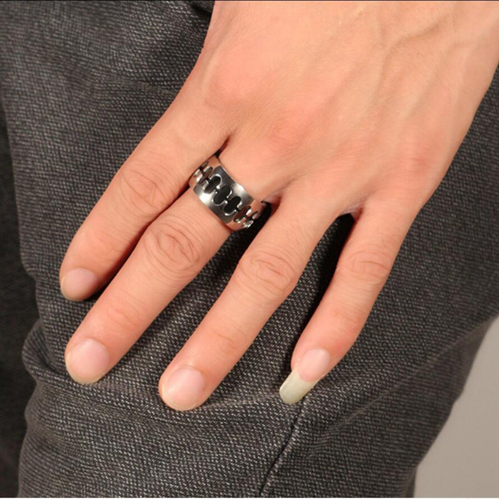 Close-up of a hand wearing a vintage stainless steel band ring with punk style design.