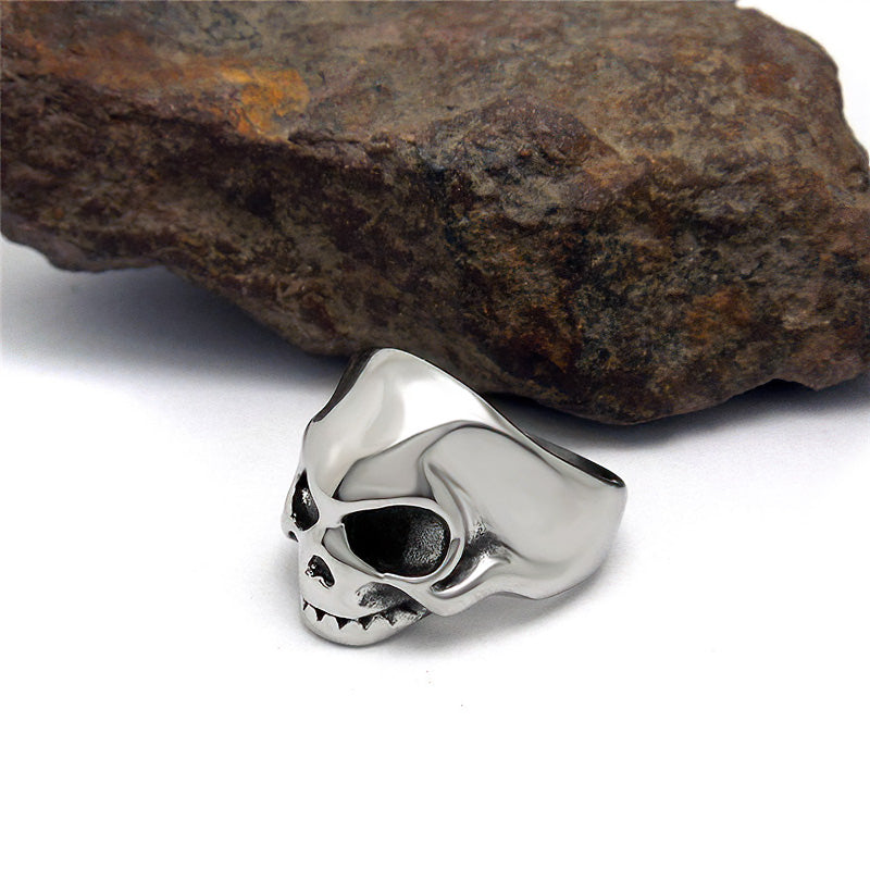 Vintage stainless steel skeleton skull ring on a rocky surface, perfect for alternative fashion and rock style jewelry.