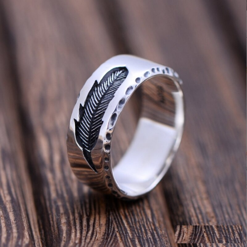 Vintage unisex sterling silver ring featuring a stylish feather design on a wooden surface.