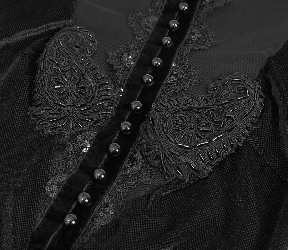 Close-up of vintage black velvet dress with intricate lace applique and button details in gothic style.