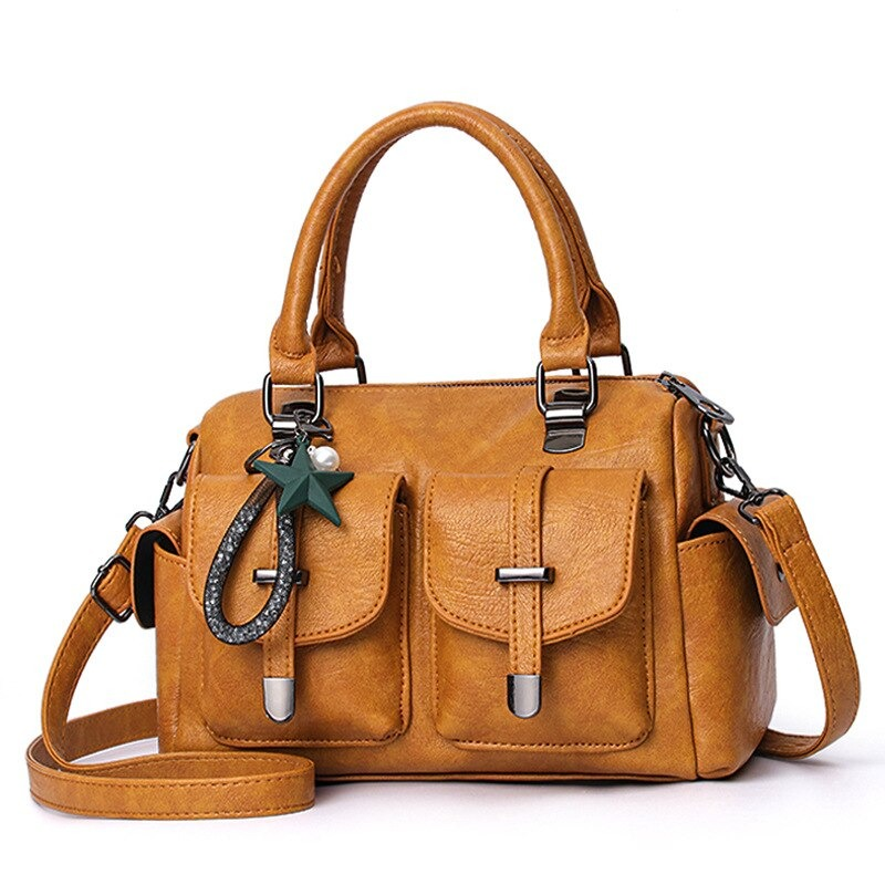 Vintage women's soft leather handbag in mustard with star pendant and multi-pocket design.