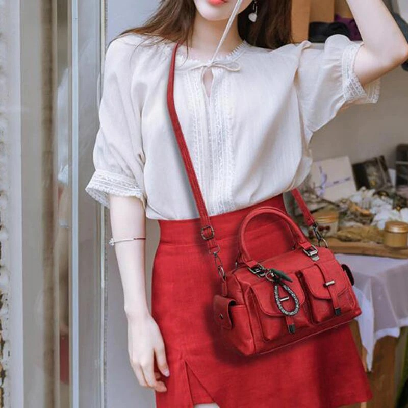 Model showcasing a vintage women handbag with star pendant, soft leather, red color, paired with stylish outfit.