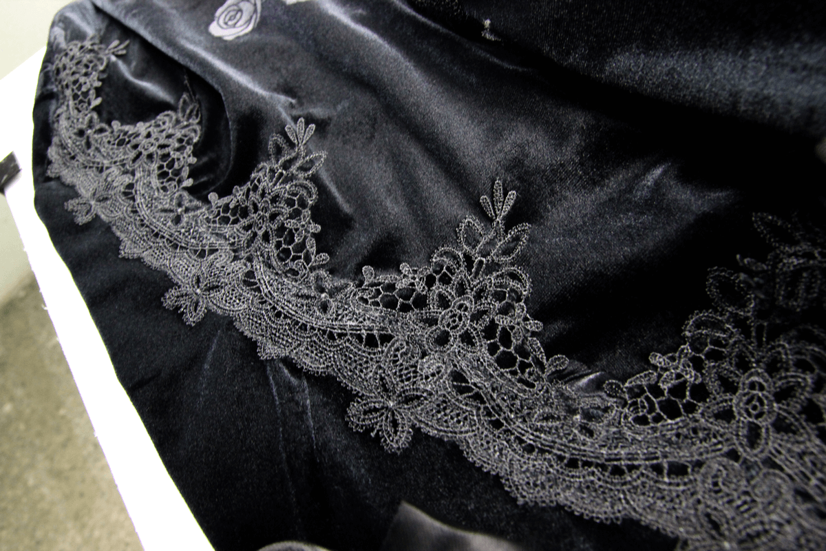 Close-up of luxurious black lace detailing on a vintage gothic skirt, showcasing intricate embroidery.