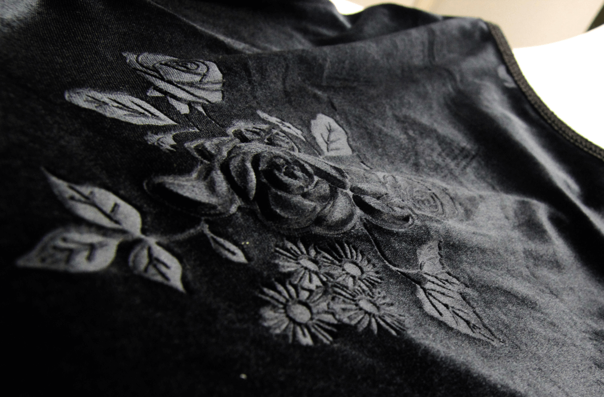Close-up of intricate black lace fabric featuring rose and daisy embroidery, perfect for vintage gothic style clothing.