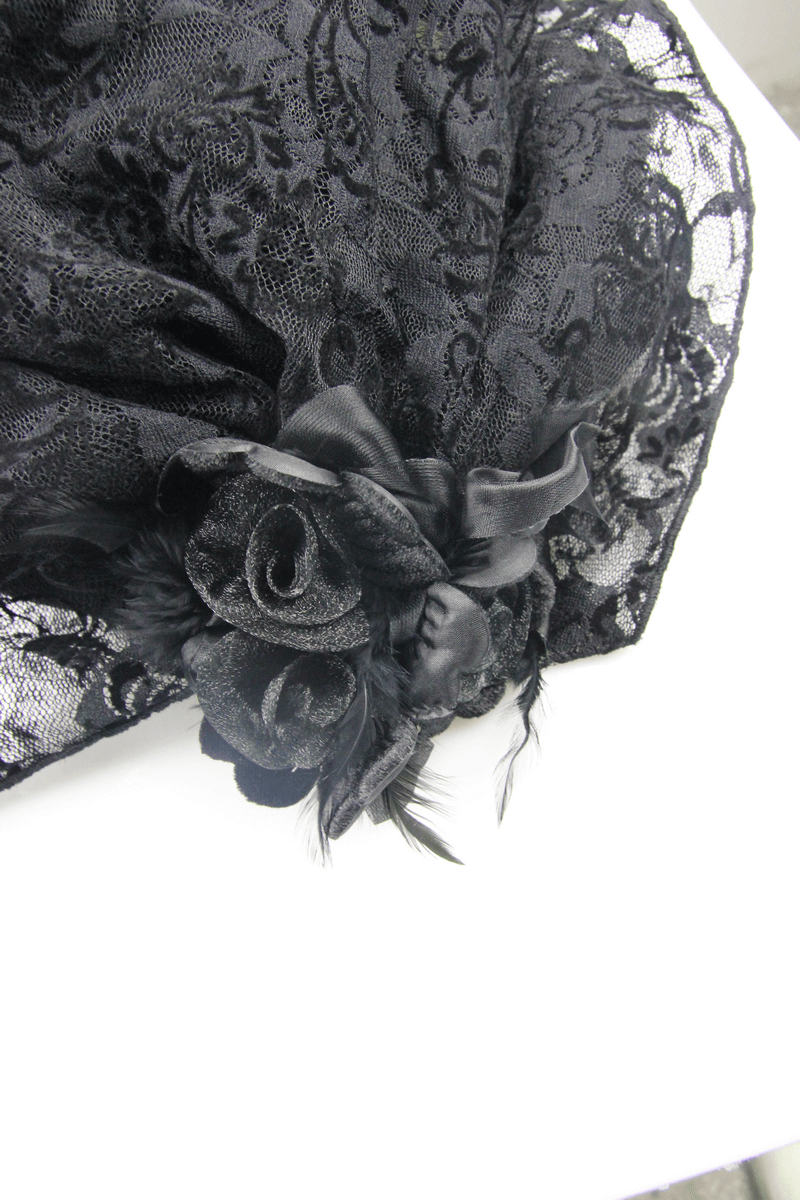 Close-up of exquisite black lace fabric with elegant rose embellishments and feathers, perfect for gothic fashion enthusiasts.