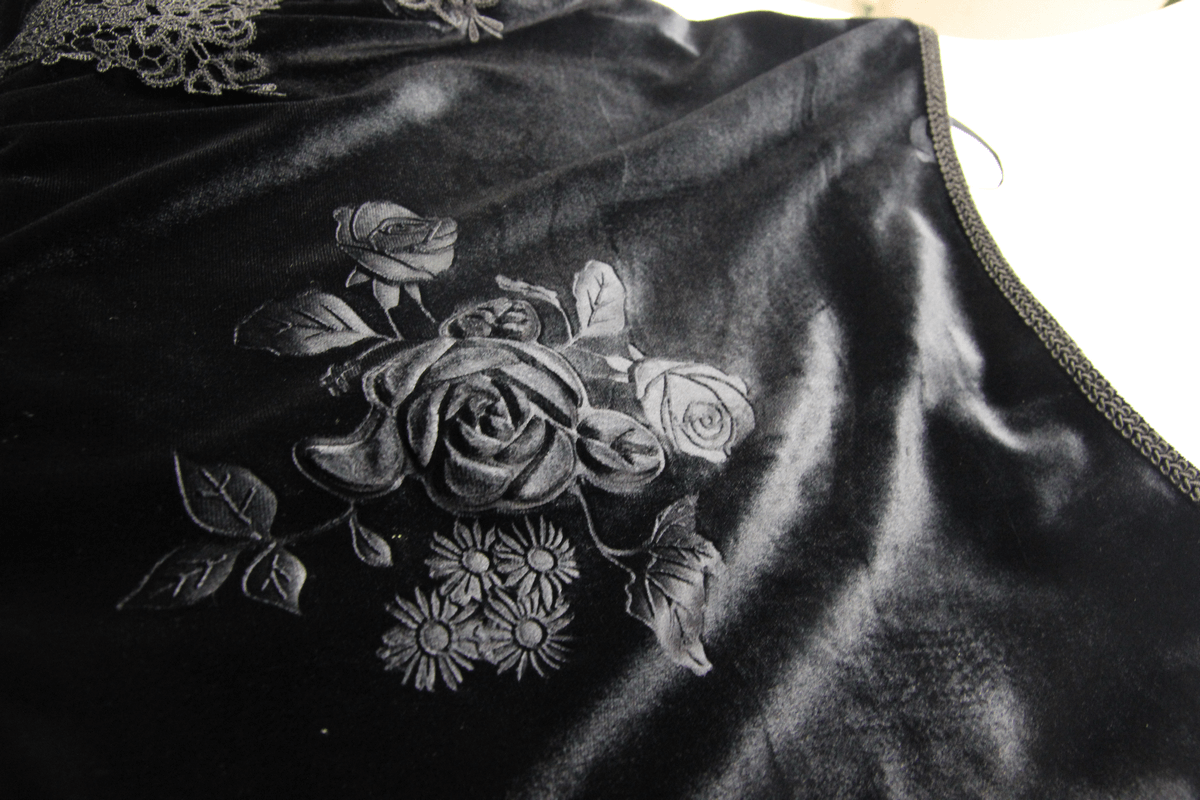 Close-up of elegant black fabric featuring intricate rose and floral embroidery, perfect for vintage goth fashion.