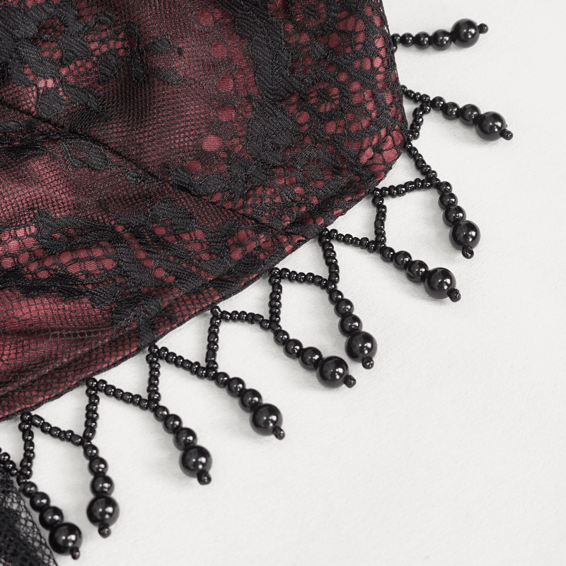 Close-up of intricate black lace and bead detailing on a wine red dress, showcasing vintage glamour.