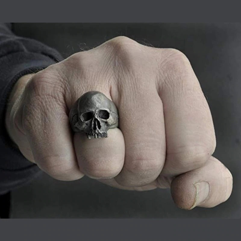 Vintage silver skull ring on a clenched fist, showcasing gothic biker jewelry style for edgy outfits.