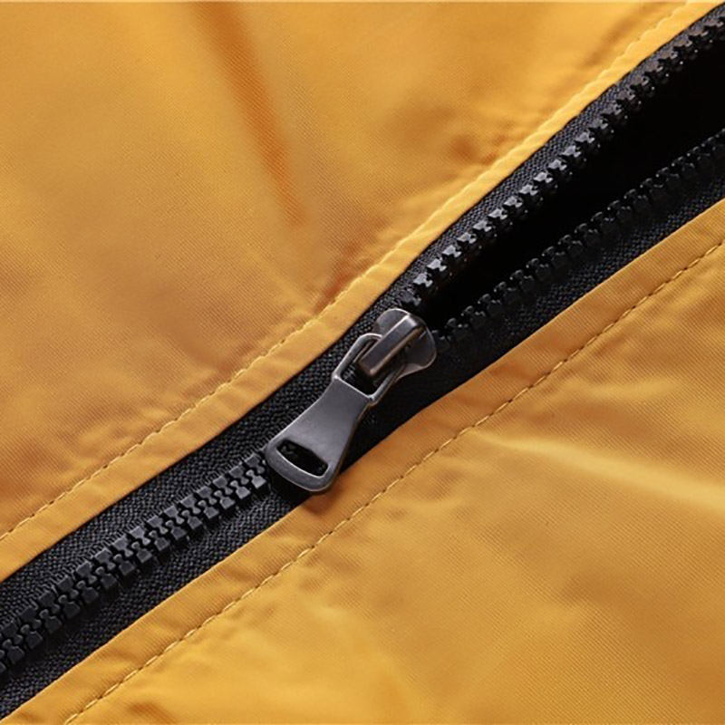 Close-up of a zipper on a water-resistant solid color men's bomber jacket in yellow.