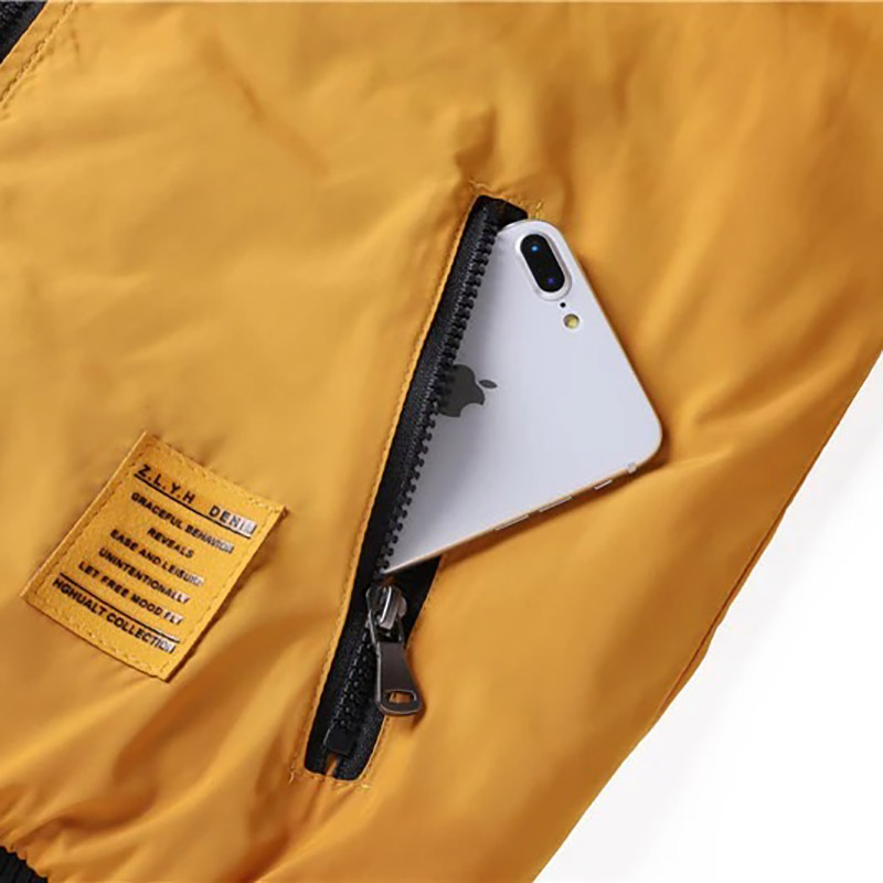 Close-up of a water-resistant men's bomber jacket zipper pocket with smartphone inside.