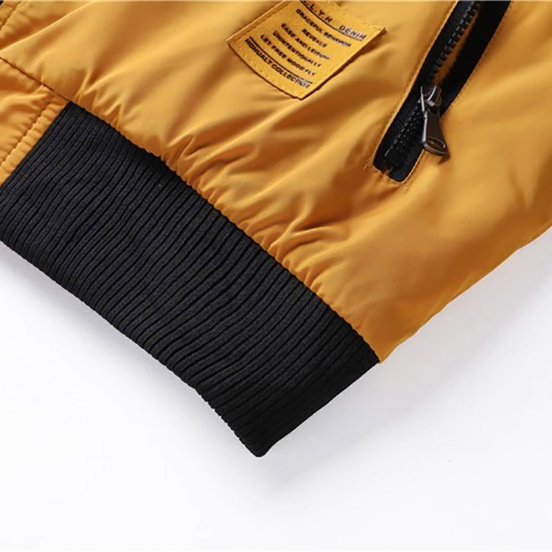 Close-up of water-resistant men's bomber jacket with black ribbed cuffs and yellow fabric finish.