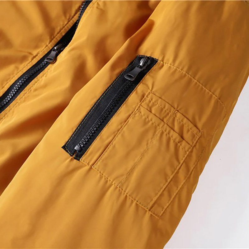 Close-up of water-resistant men's bomber jacket in mustard color featuring zippered pockets and a smooth finish.