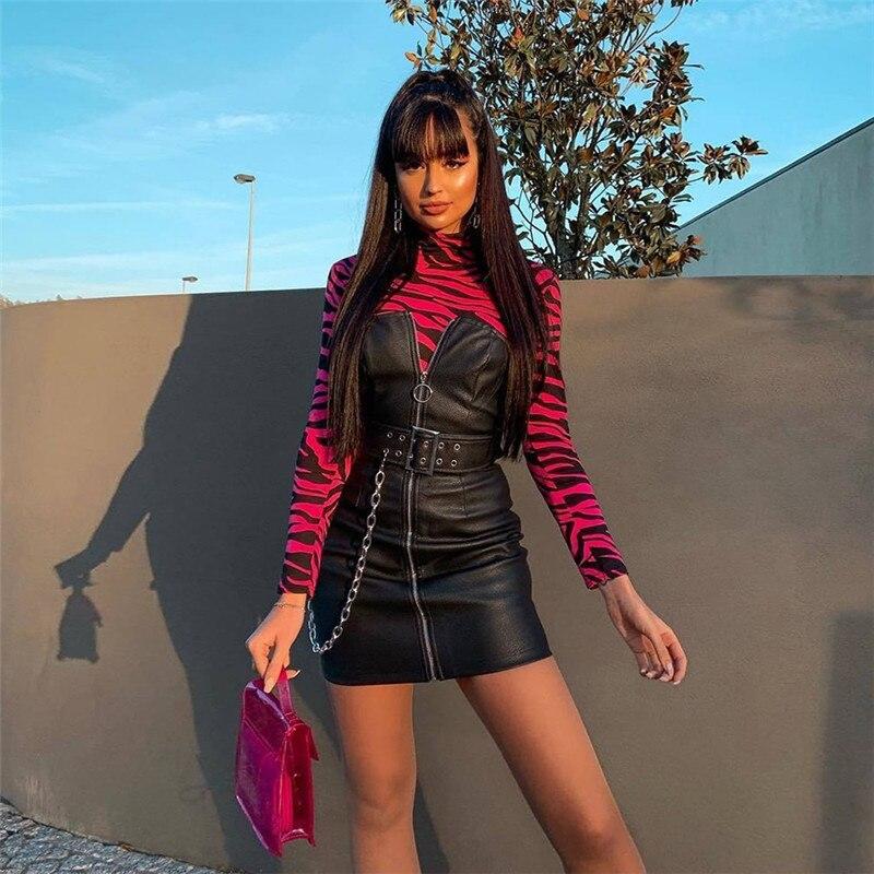 Stylish woman in a Gothic style off-shoulder dress with chain, standing confidently against a trendy backdrop.