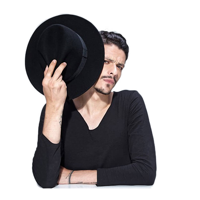 Man in black shirt holding a wide brim wool fedora, showcasing alternative fashion style.