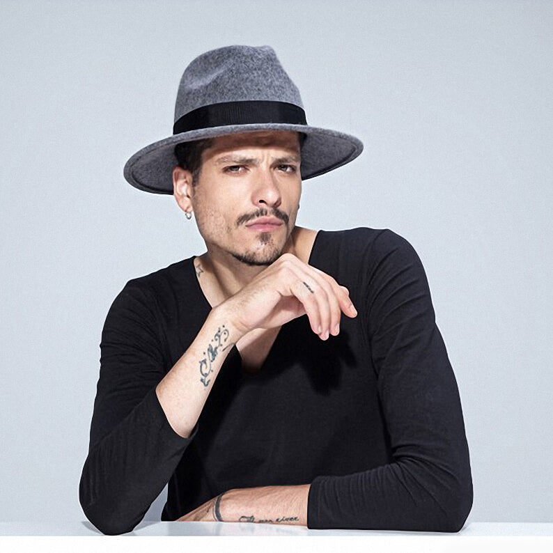 Stylish man wearing a wide brim gray wool fedora hat against a minimalist backdrop, perfect for alternative fashion.