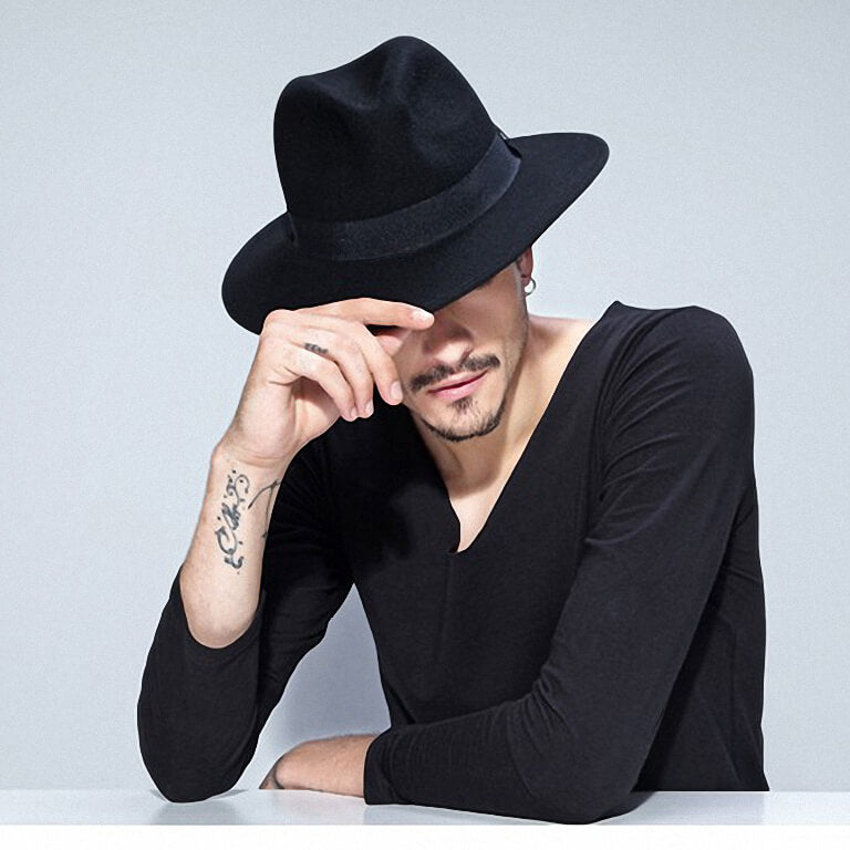 Stylish man wearing a wide brim black wool fedora hat and a black long sleeve shirt, perfect for rock fashion.