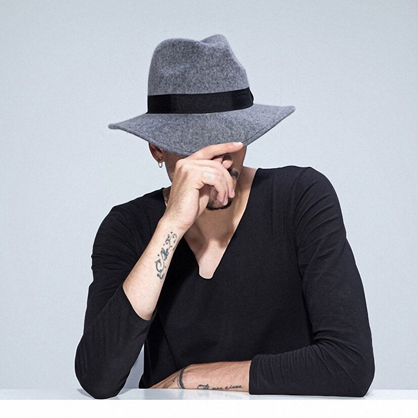 Stylish gray wide-brim wool hat with black band worn by a man in a black long-sleeve shirt, showcasing alternative fashion.