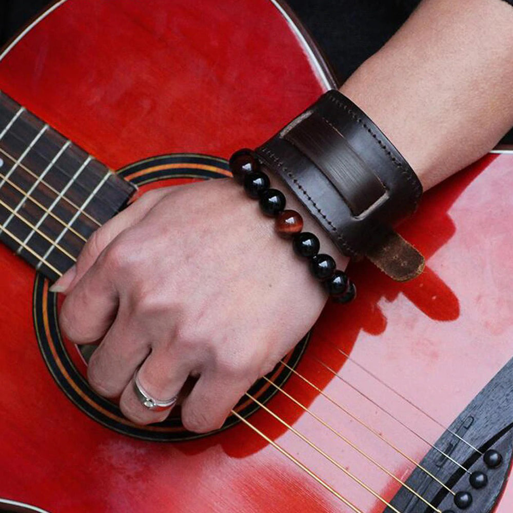 Stylish unisex vintage leather bracelet worn on a hand holding an acoustic guitar, showcasing rock-inspired accessories.