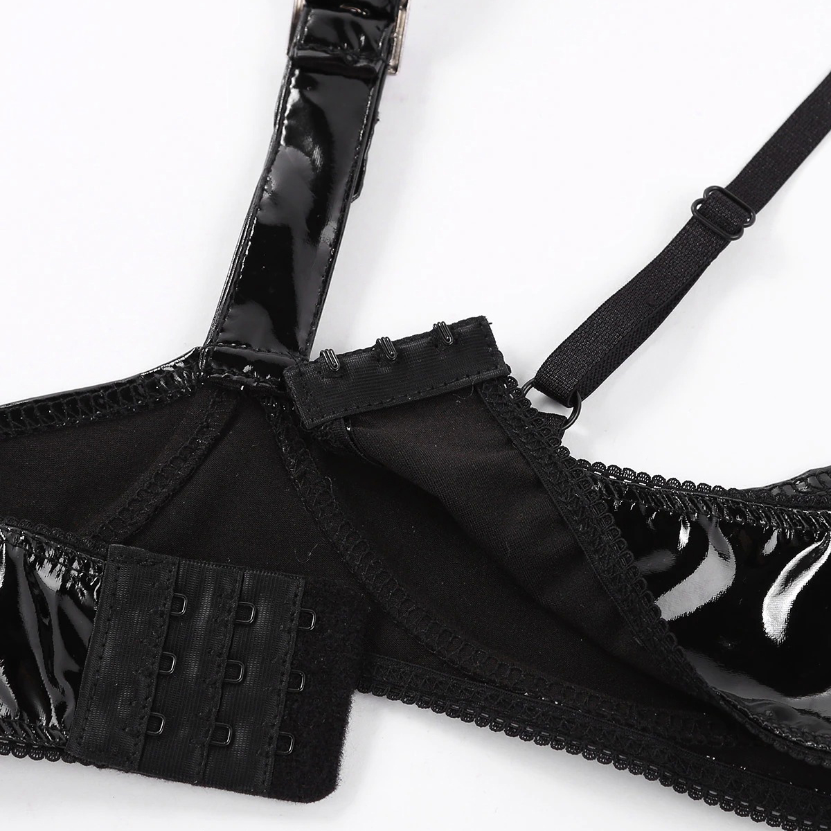 Close-up of wire-free patent leather women's open cup bra with halter neck and buckle detailing.