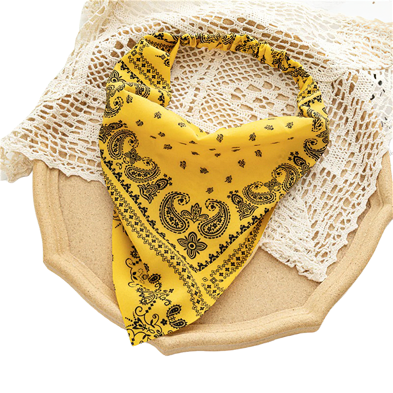 Stylish yellow women's bandana with printed design laid on a textured plate, perfect casual hair accessory.