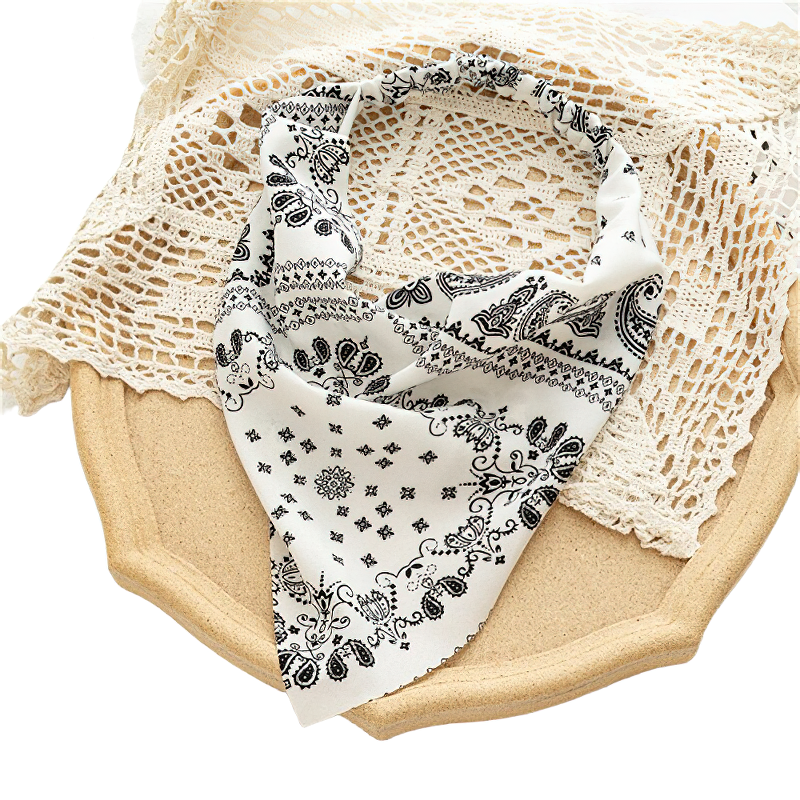 Stylish women's black and white printed bandana resting on a crochet lace background, perfect casual hair accessory.