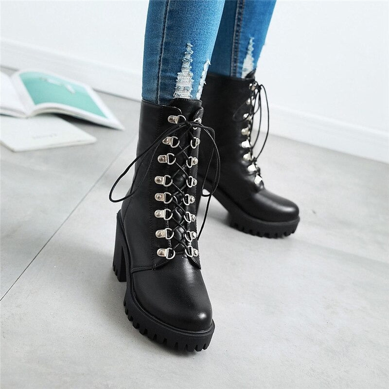 Stylish woman's black fashion boots with square heel and lacing, paired with ripped jeans for a trendy look.