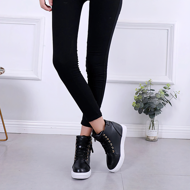 Stylish women's black ankle boots with laces and side zipper, paired with black leggings in a modern setting.