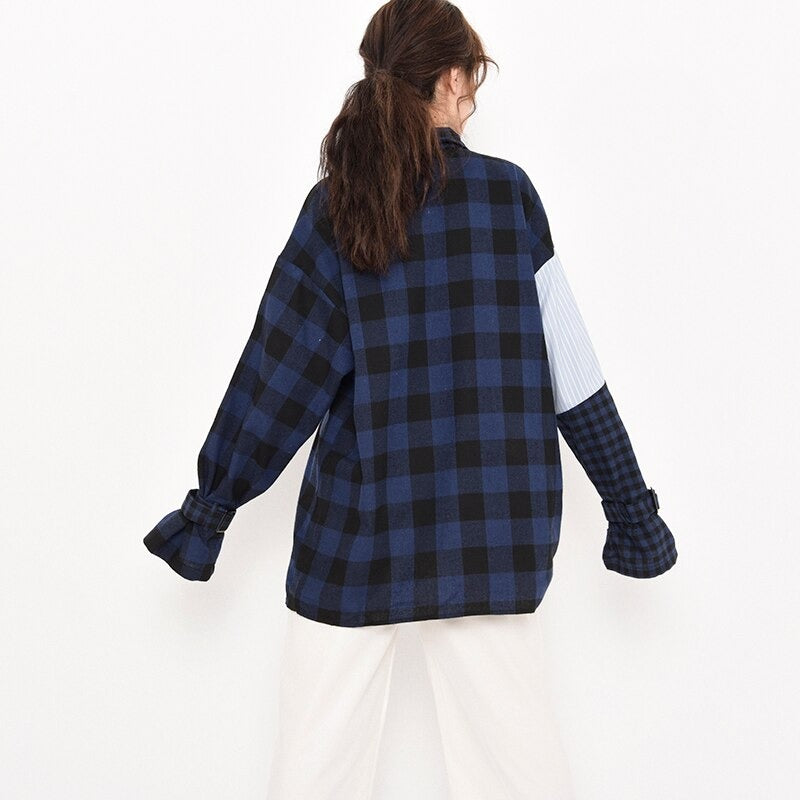 Back view of a woman in a blue striped plaid oversized shirt with long sleeves, showcasing grunge fashion style.