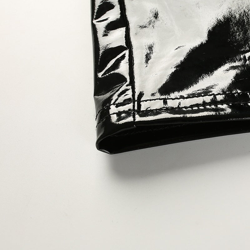 Close-up of a shiny black synthetic leather fabric, showcasing its glossy texture for a trendy women's crop top.