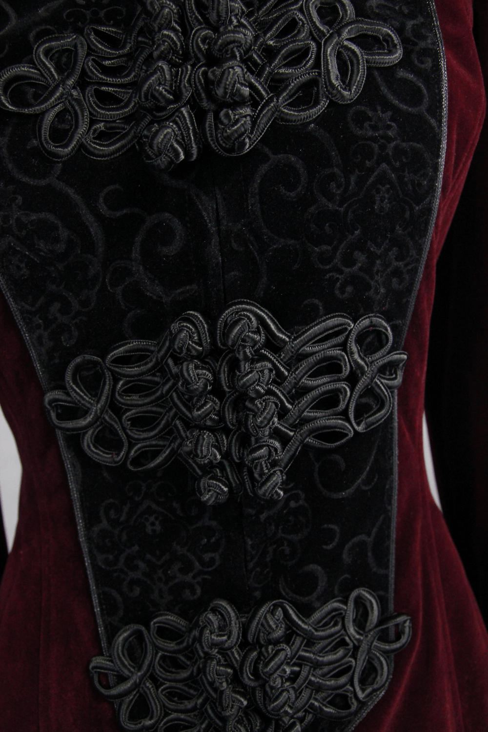 Close-up of intricate black lace detailing on a gothic-style long red coat, showcasing vintage elegance.