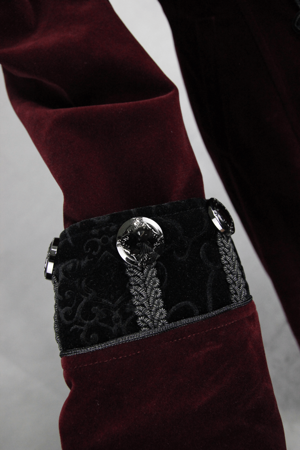 Close-up of the sleeve detail on a women's gothic red coat, featuring elegant black lace and decorative buttons.
