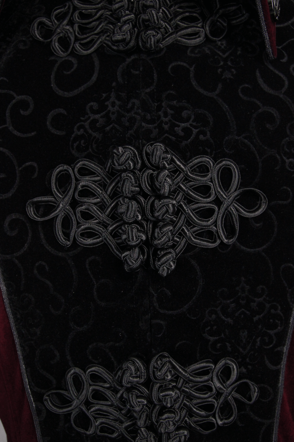 Close-up of intricate black lace detailing on a gothic red women's coat, showcasing stylish vintage craftsmanship.