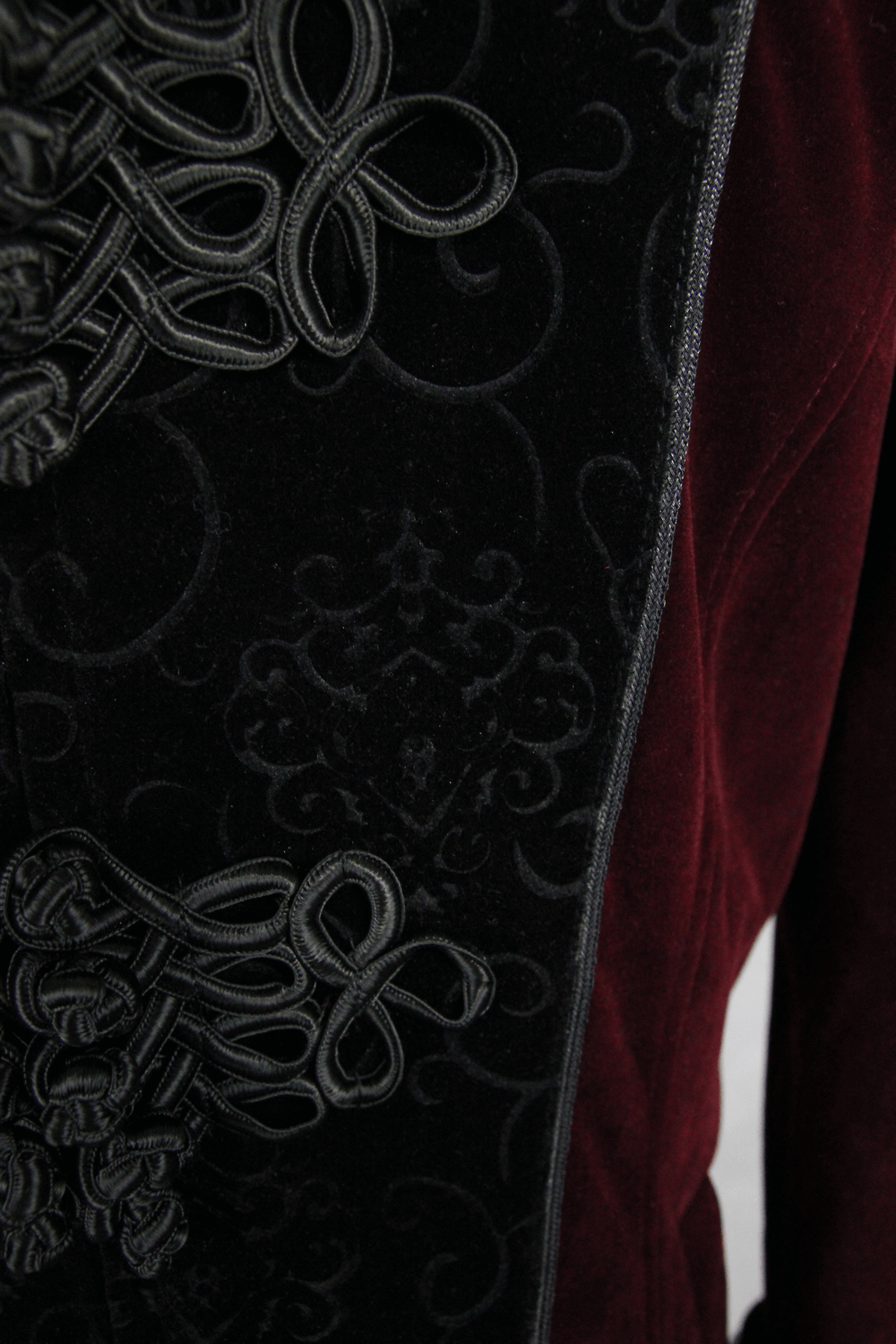 Close-up of a gothic style women's red coat with lace and intricate black embroidery details.