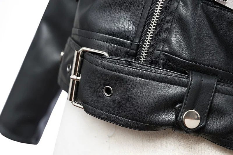 Close-up of adjustable belt on women's faux leather biker jacket, showcasing sleek design and stylish zippers.