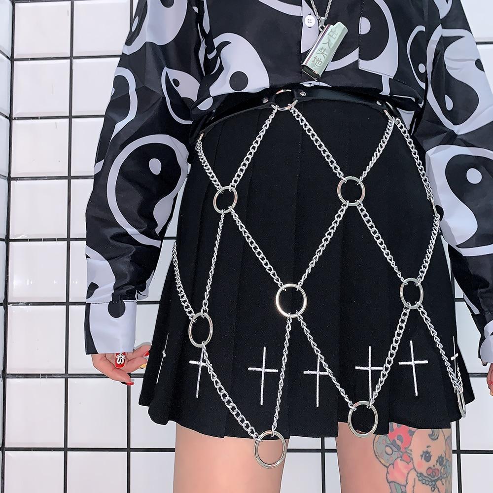 Women’s faux leather body harness with chains, styled over a black skirt, embodying rock star fashion vibes.