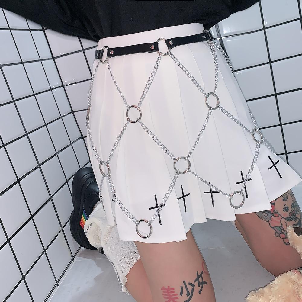 Women wearing a faux leather body harness with chains over a white skirt, embodying rock star fashion style.