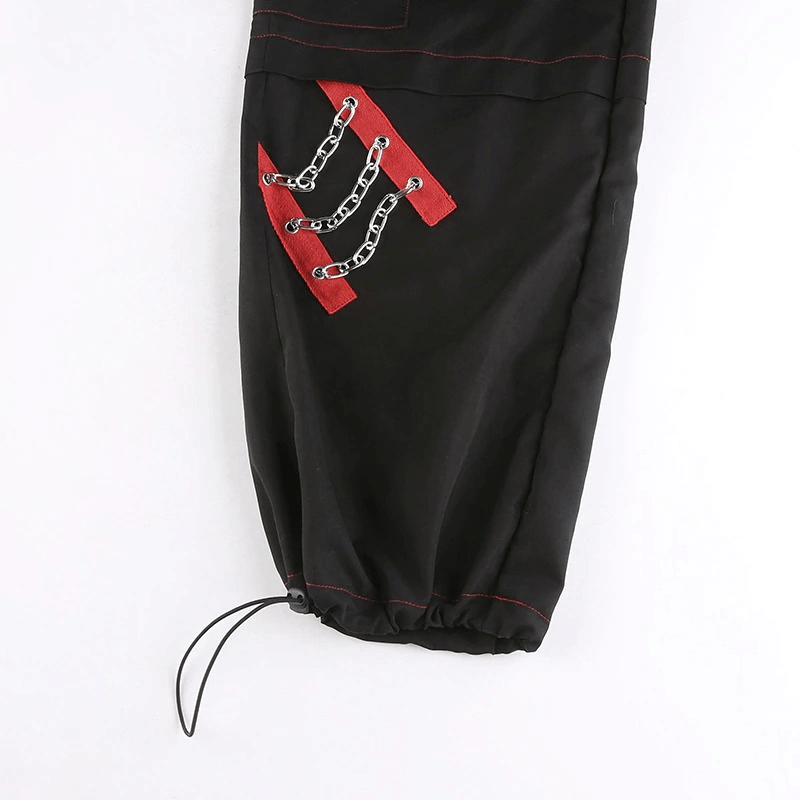 Close-up of women's black wide-leg cargo pants featuring punk-style chain detail and stylish red stitching.