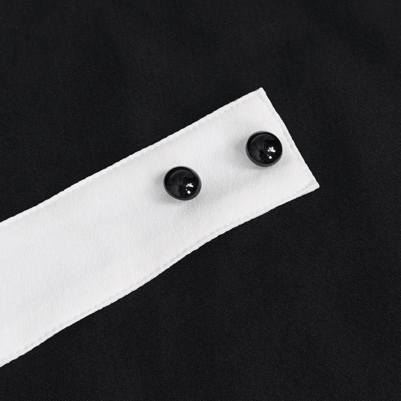 Close-up of black fabric with white ruffled necktie insert and two decorative black buttons.