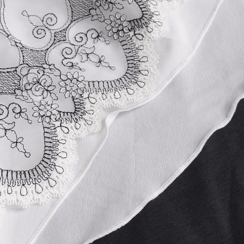 Close-up of gothic floral embroidered necktie with ruffles in black and white fabric.