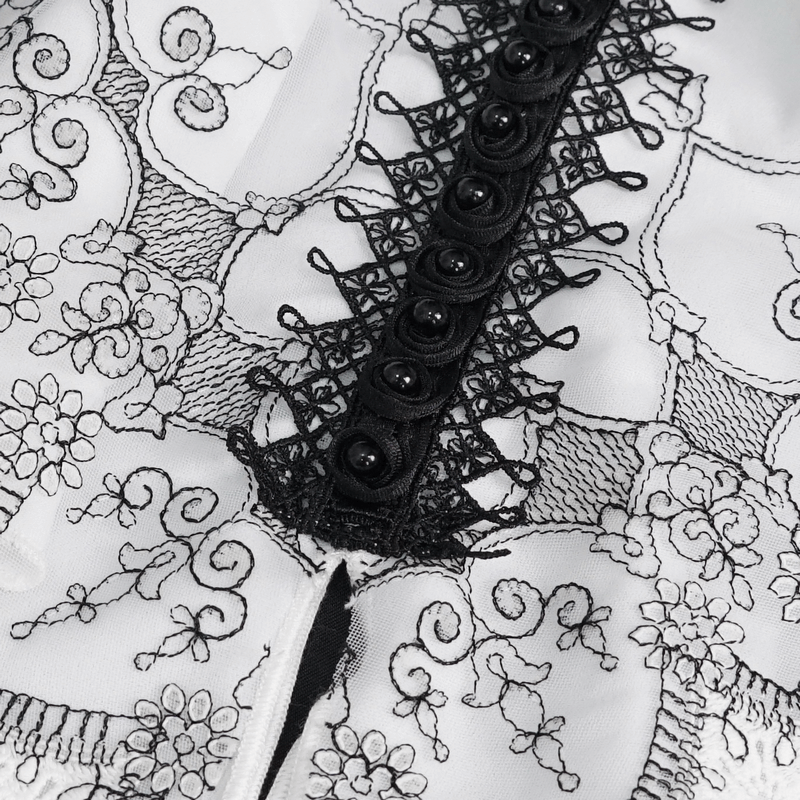 Close-up of gothic black and white floral embroidered necktie featuring ruffled accents and decorative buttons.
